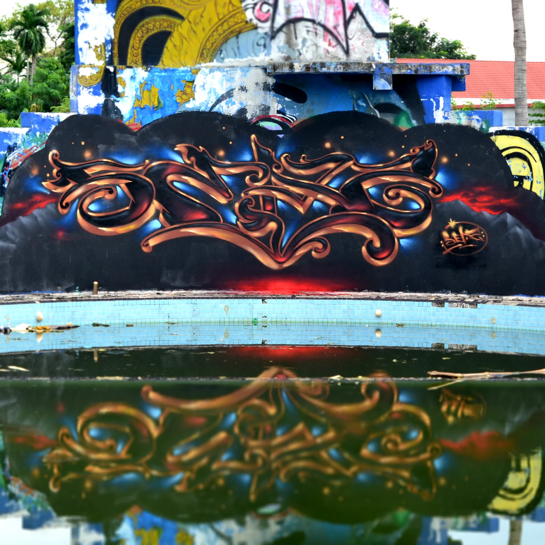 Ornate SEAZ tag piece painted beside a drained pool, reflected in standing water