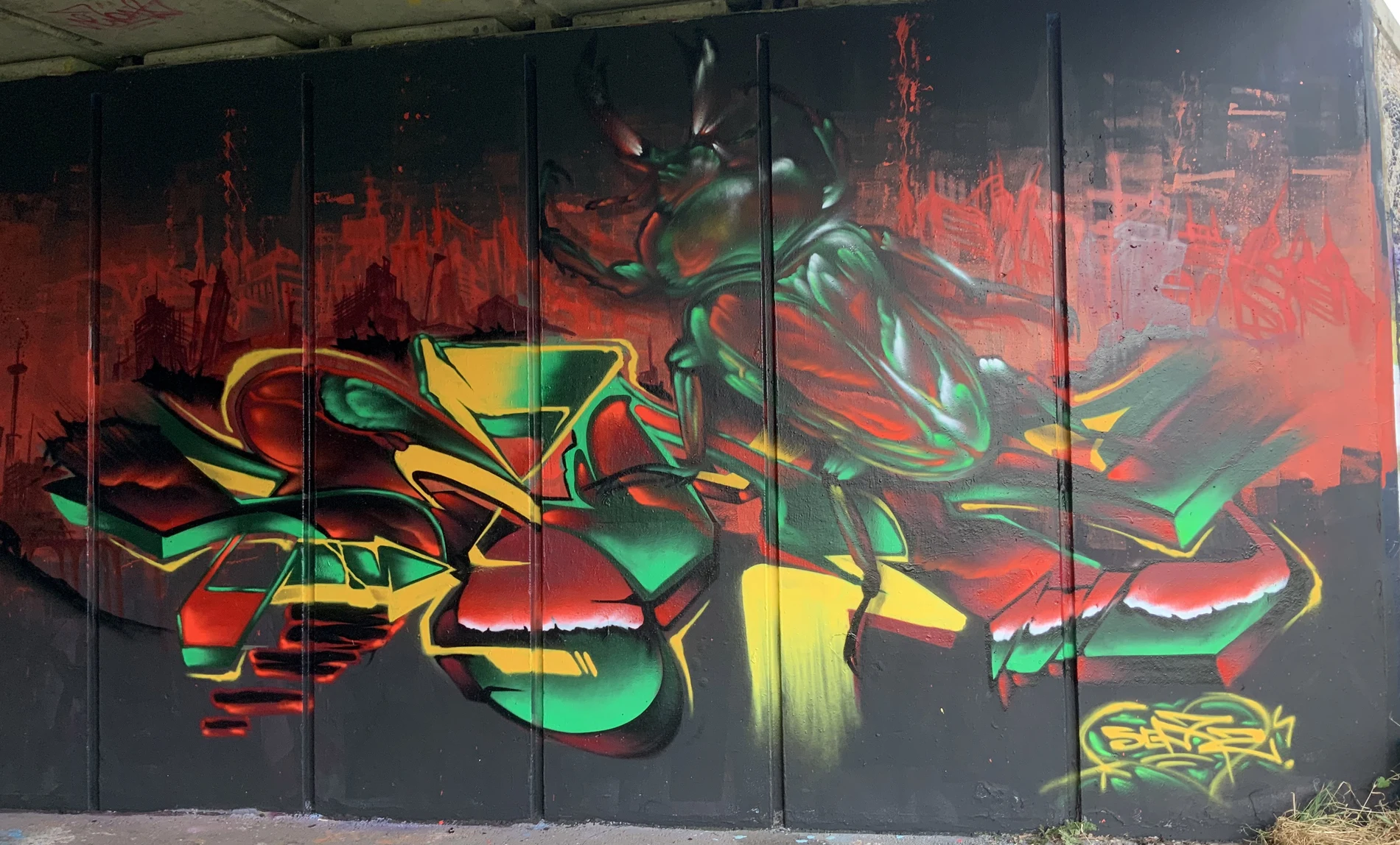 Bold beetle and graffiti letterform mural under a bridge in Tamworth, UK