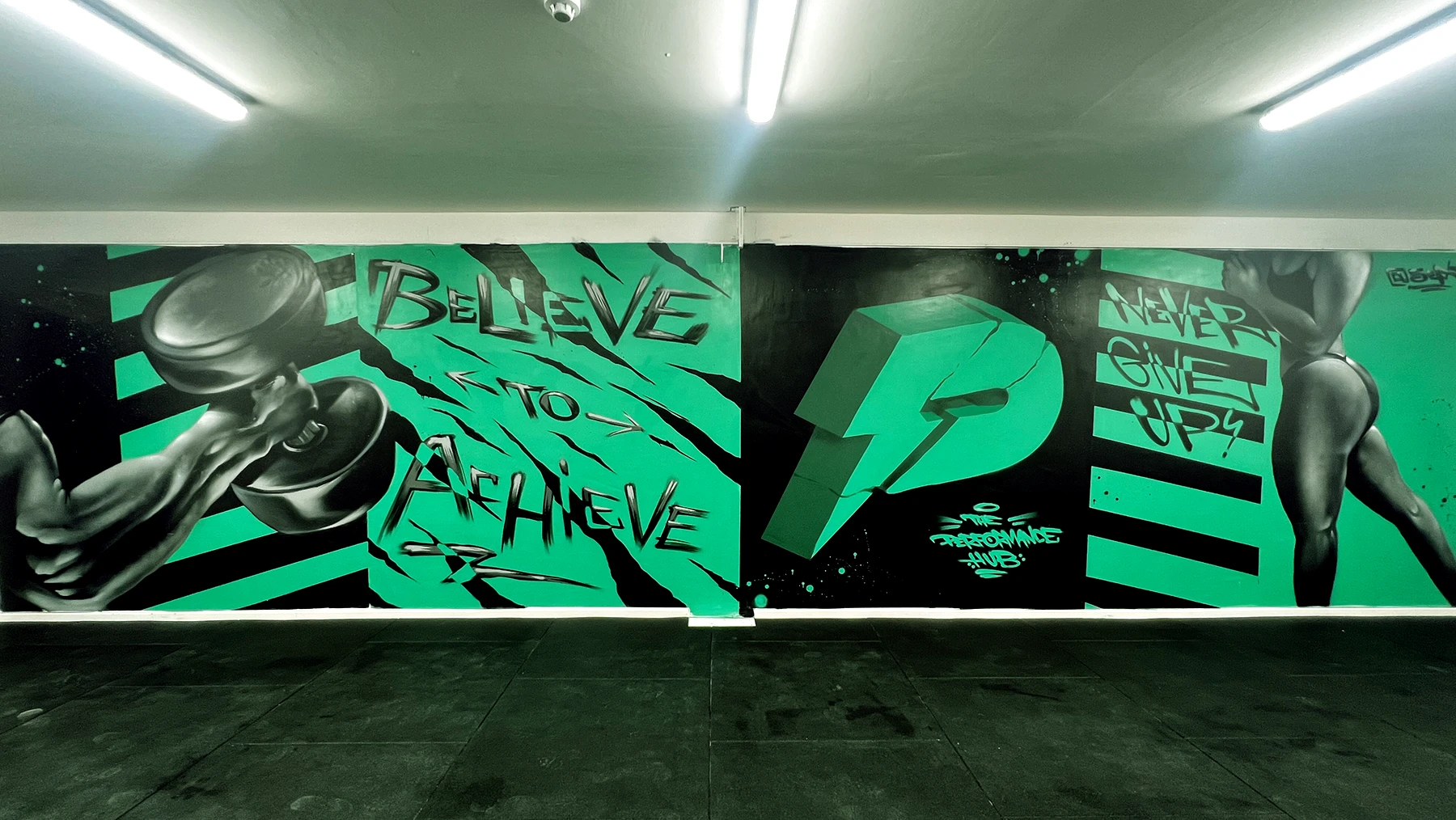 The Performance Hub hand-painted gym mural reading 'Believe to Achieve'